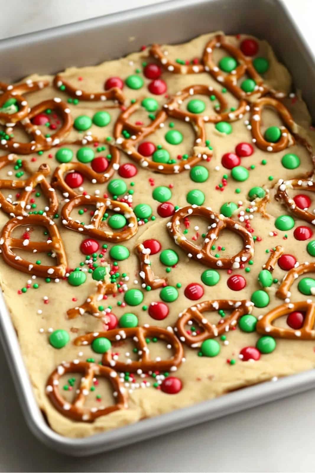 These festive Christmas cookie bars are loaded with chocolate chips, M&Ms, pretzels, caramels, and holiday sprinkles for the ultimate holiday treat. Soft, chewy, and easy to make, they’re perfect for parties or gift-giving!