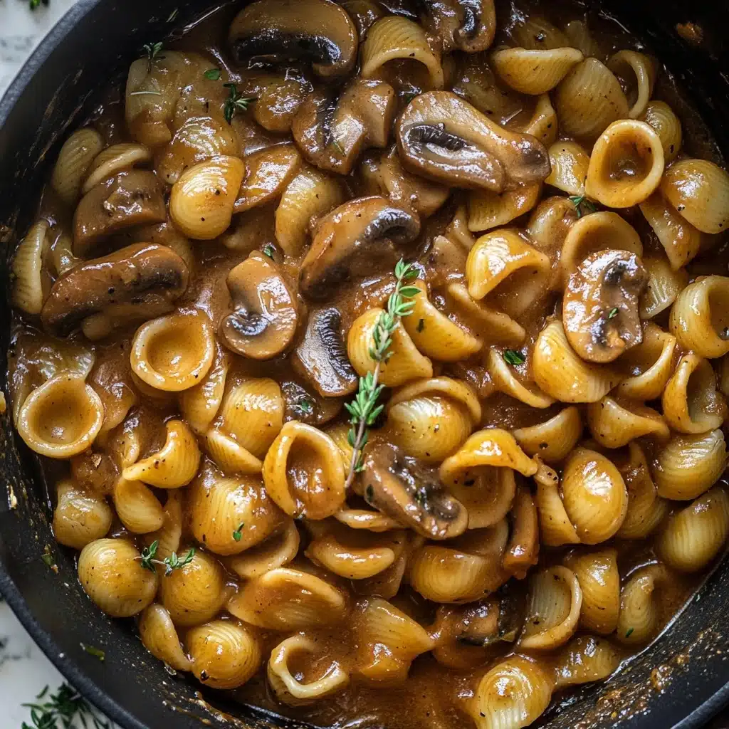 One Pot French Onion Pasta, French Onion Pasta, Easy Pasta Recipes, Comfort Food Recipes, One Pot Pasta Dinners The dish shows a close-up view of orecchiette pasta coated in a thick, glossy brown sauce with visible slices of mushrooms mixed throughout. The pasta appears tender and well-cooked, with a smooth texture, while the mushrooms are slightly darker and shiny, blending into the sauce. Small sprigs of fresh thyme are scattered over the top, adding a touch of green for contrast. There are no visible layers, and all the ingredients are mixed evenly in a single, rustic layer inside a dark pot, shot from above on a white marbled texture.
