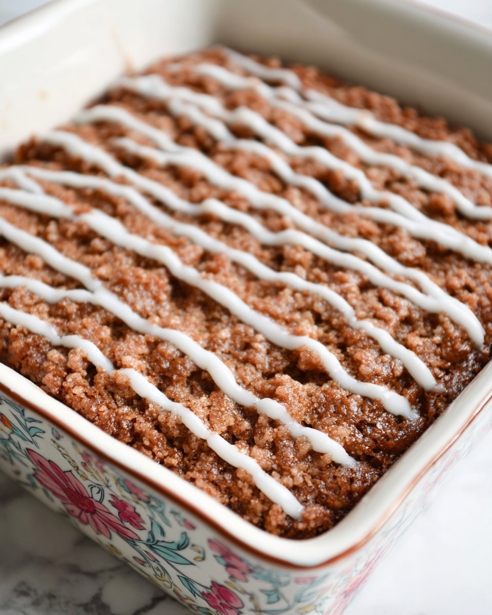 A square piece of crumb cake with three layers is shown on a white plate: the bottom and top layers are light golden brown cake, the middle layer is dark purple berry filling, and the top layer has a crumbly, brown streusel texture with white icing drizzled on top. In the foreground, a small piece of cake with the same layers is on the plate next to a wooden-handled fork. In the background, there are blurred pieces of the same cake and a glass of milk. The setting is on a white marbled surface. Photo taken with an iphone --ar 4:5 --v 7