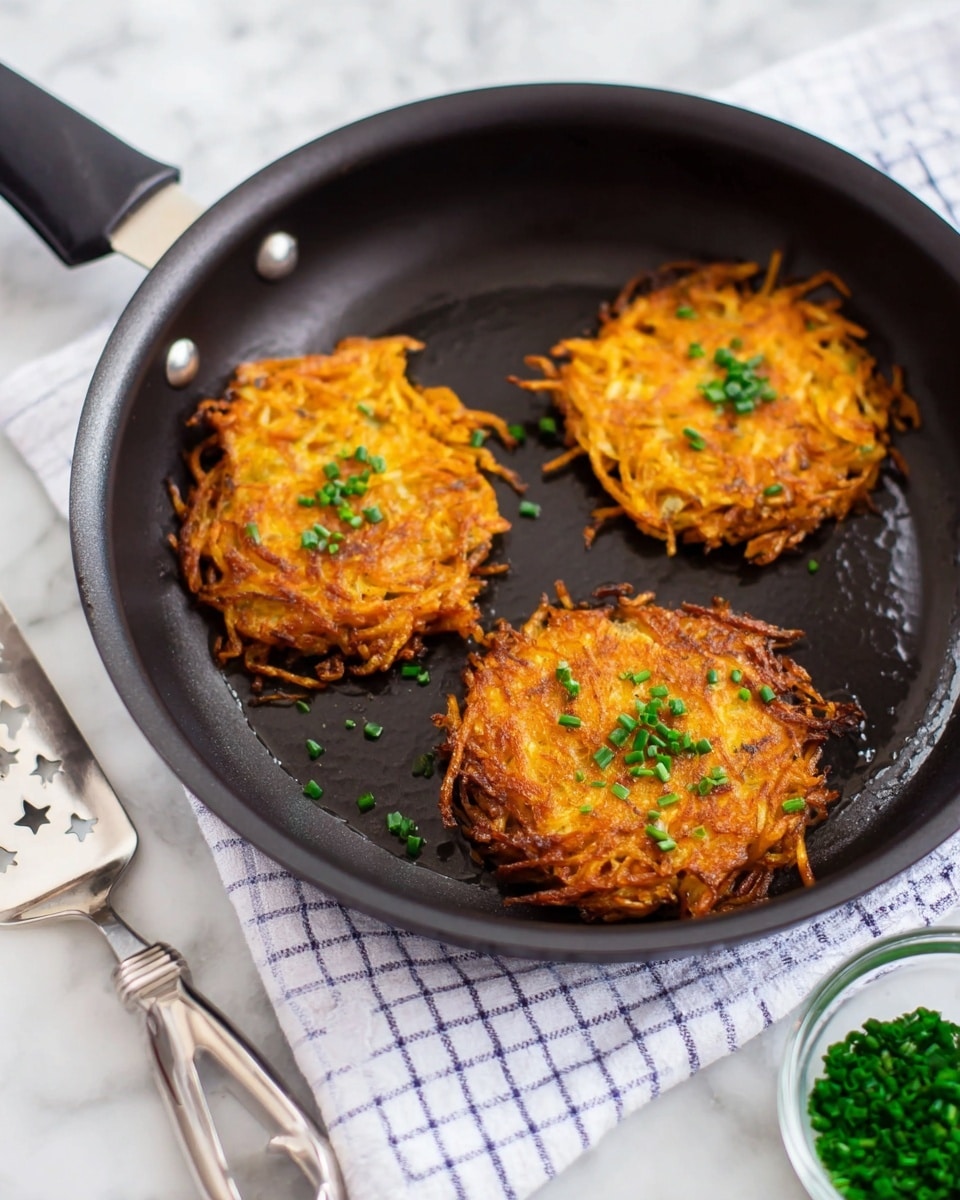 The image shows a white plate with two crispy orange potato pancakes sprinkled with small green chive pieces, placed next to three strips of brown cooked bacon at the top left corner. Below the plate is a black cast iron pan containing three more golden browned potato pancakes, each topped with small green chives. The pan is resting on a white cloth with navy blue check lines over a white marbled surface. To the left of the pan are two vintage-style silver forks resting on the cloth, and to the right is a small clear bowl with chopped green chives. photo taken with an iphone --ar 4:5 --v 7