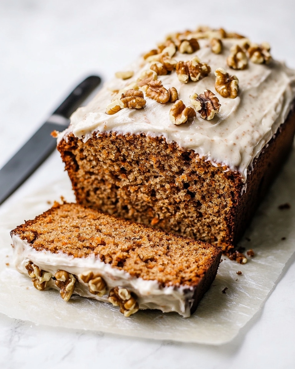 A loaf of carrot nut bread is shown with two slices cut from the front. The bread has a dense, brown crumb with visible pieces of carrot and nuts inside. The top layer is covered with a thick layer of creamy white frosting, sprinkled with walnut halves. The loaf and slices sit on a piece of parchment paper against a white marbled surface, with a dark knife placed near the back of the loaf. The texture of the bread is moist and rough, contrasting with the smooth frosting and crunchy walnuts on top. Photo taken with an iphone --ar 4:5 --v 6.1