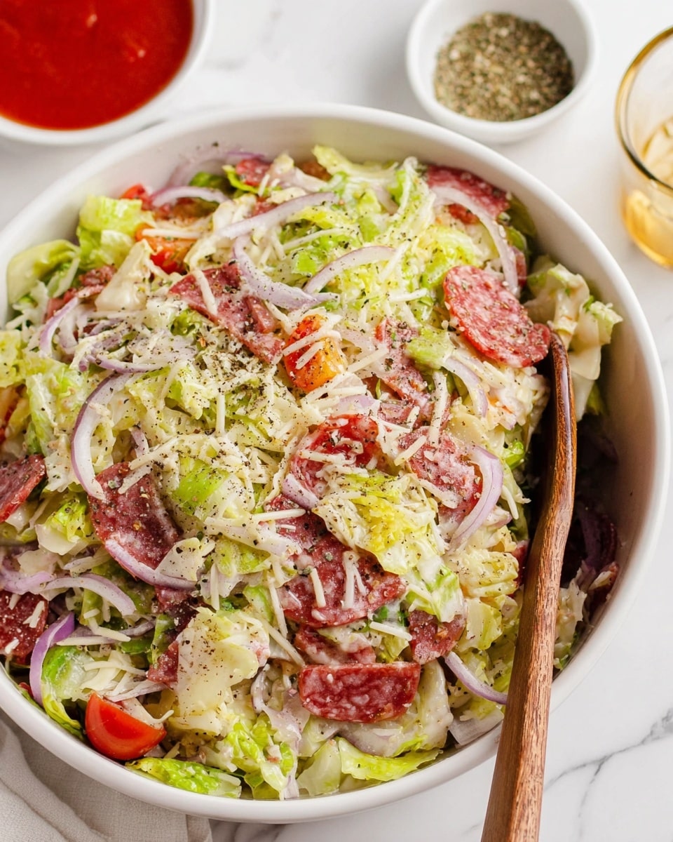 The dish shows a close-up of a mixed salad served in a white bowl resting on a white marbled surface. It has multiple layers, starting with a base of shredded green and light yellow lettuce that appears fresh and crisp. Mixed within the lettuce are thin slices of reddish-pink cured meat, likely salami, adding a contrast with their slightly glossy texture. Scattered throughout are small, bright red cherry tomato halves, and pieces of diced white cheese or similar creamy elements. Thin slices of purple onion add a touch of sharpness and color diversity. The salad looks lightly coated with a creamy dressing that gives a soft, moist look. The vibrant colors and variety of textures make the salad look fresh and appetizing. Photo taken with an iphone --ar 4:5 --v 7
