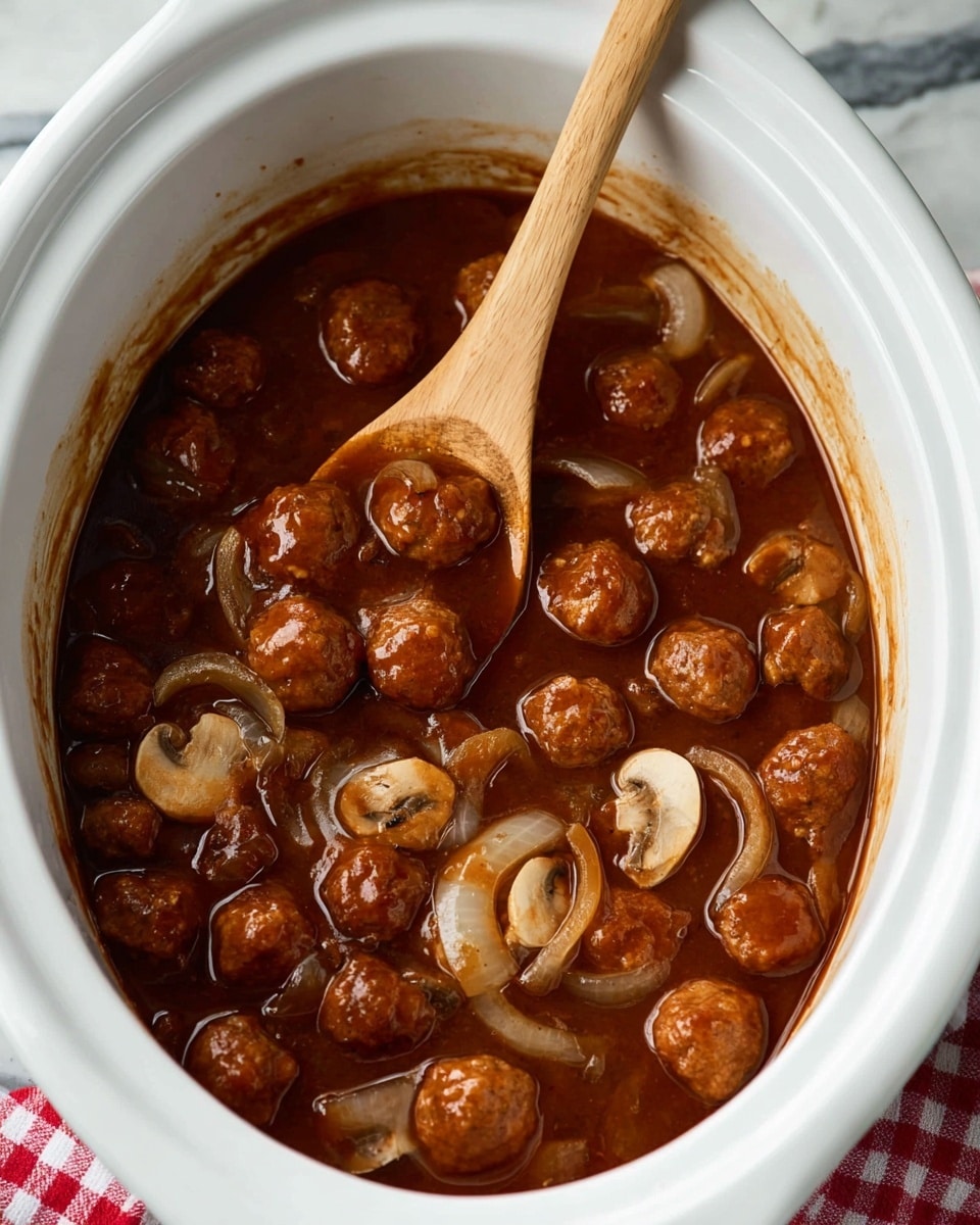 A white oval slow cooker filled with a rich brown sauce containing small round meatballs, sliced mushrooms, and thinly sliced onions. A wooden spoon is partially submerged in the sauce, lifting some of the meatballs and onions. The sauce has a glossy texture, and the ingredients are evenly spread in the slow cooker, which sits on a white marbled surface with a red and white checkered cloth nearby. Photo taken with an iphone --ar 4:5 --v 7
