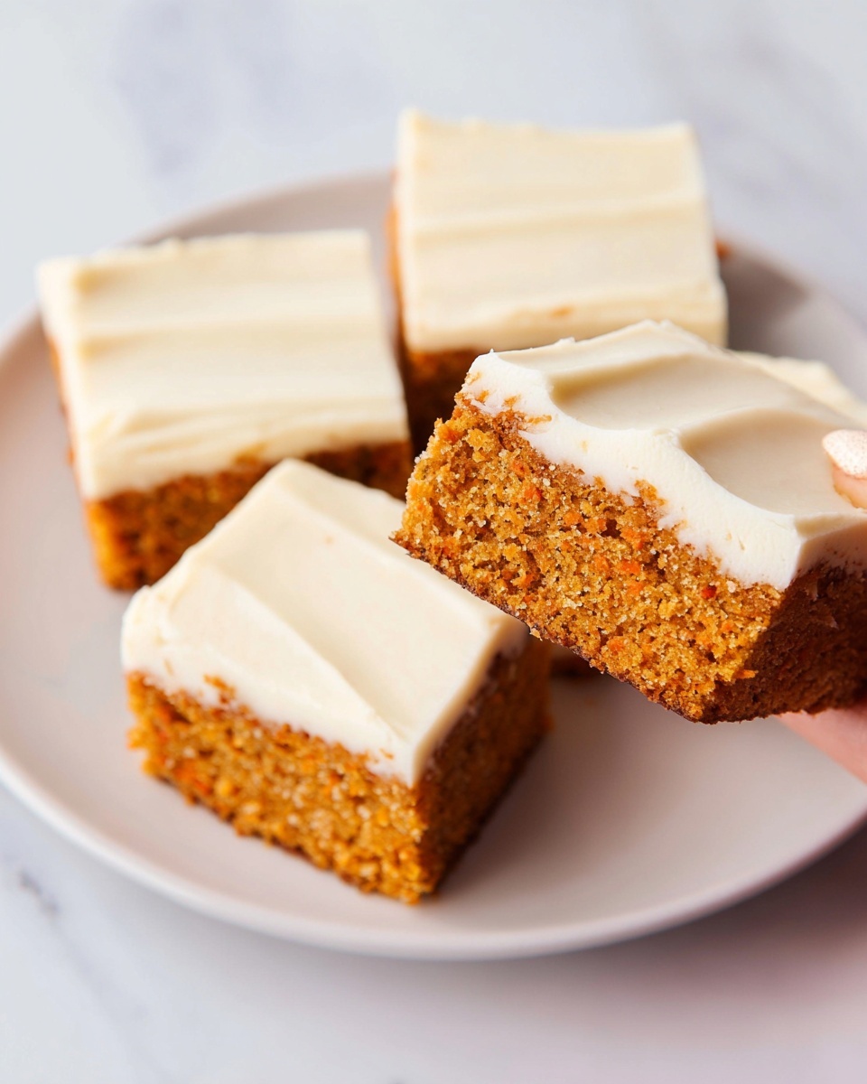 The image shows four square pieces of carrot cake with two layers each, placed on a white plate over a white marbled surface. Each piece has a moist-looking orange-brown cake bottom layer with a light texture and tiny holes. The top layer is thick and creamy with smooth, white frosting. One piece is lifted slightly above the plate in a woman's hand, showcasing the cake and frosting layers clearly. The frosting on each piece is evenly spread with soft swirls, and a few crumbs lightly dust the frosting edge. Photo taken with an iphone --ar 4:5 --v 7