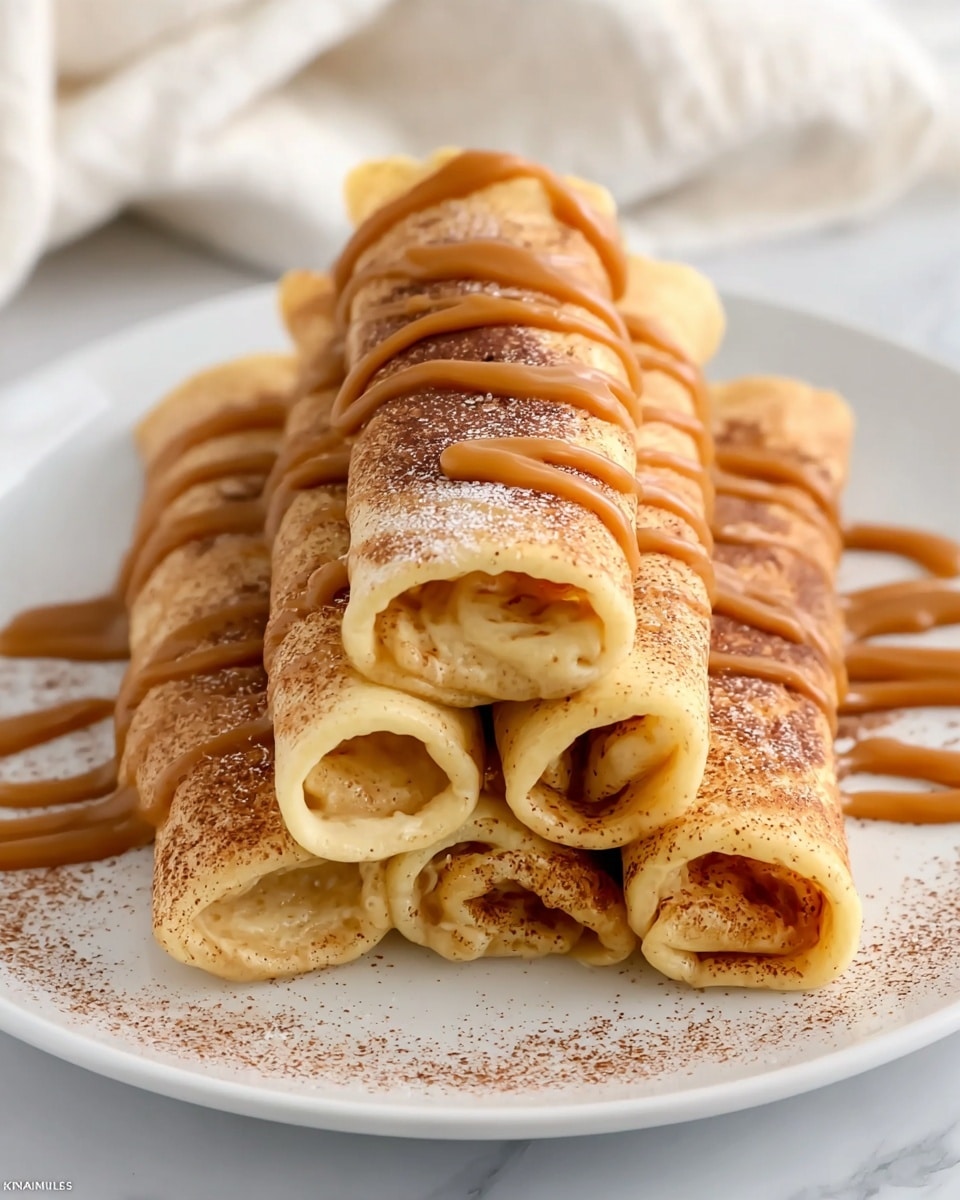 A white round plate shows five rolled crepes stacked in a pyramid shape with two on the bottom, two in the middle, and one on top. The crepes are light golden brown, soft, and slightly spongy in texture. They are dusted with a fine layer of brown cinnamon powder all over. Rich caramel-colored sauce is drizzled in thick, smooth lines diagonally across the top five crepes, creating waves of glossy texture. The background is a soft white marbled surface with a hint of a white cloth in the distance. Photo taken with an iphone --ar 4:5 --v 7