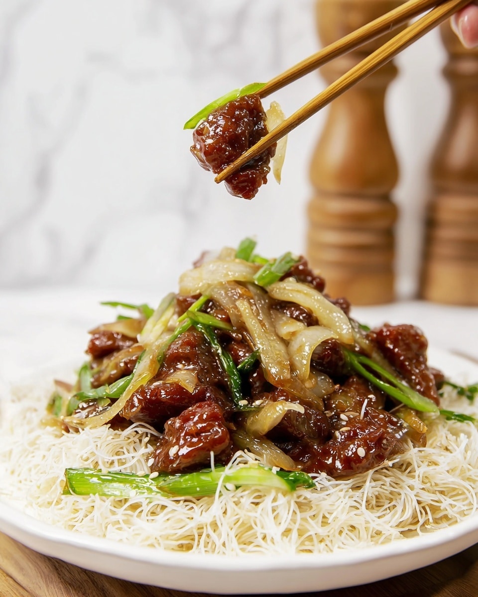 The image shows a white bowl with three main layers. The bottom layer is a nest of thin, crispy white rice noodles, looking light and crunchy. On top of the noodles, there is a mix of cooked beef slices, which are dark brown and shiny with a glossy garlic sauce coating, adding a moist and flavorful look. Scattered among the beef slices are slightly cooked, translucent white onion pieces and bright green scallions cut lengthwise, adding color contrast. In the background, there is a white marbled surface with a blurred wooden pepper grinder and a white sugar container. Photo taken with an iphone --ar 4:5 --v 7