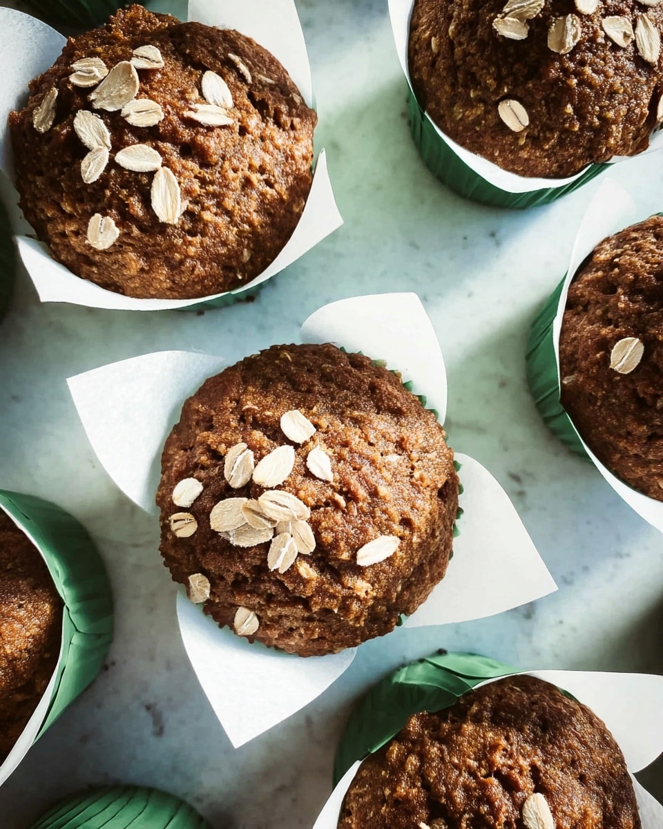 Several brown muffins with a rough texture are placed in white baking papers with green edges. Each muffin has scattered light-colored oats on top. The muffins are arranged on a white marbled surface, visible between the muffins. The lighting is bright, highlighting the muffins' surface details. photo taken with an iphone --ar 4:5 --v 7