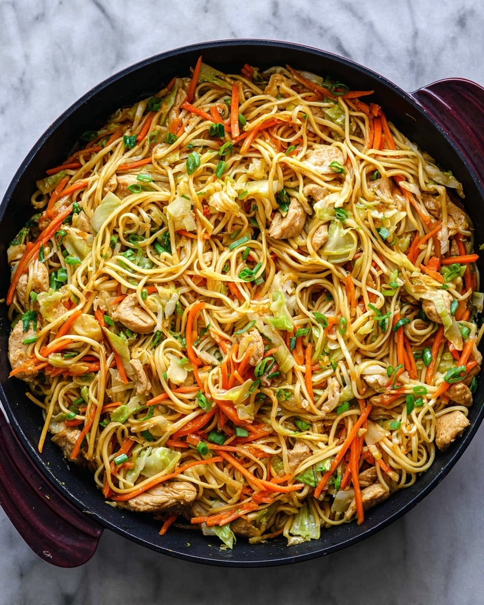 The image shows a close-up of a large black pan filled with a noodle stir-fry. The dish has a base of long, light brown noodles tangled all over the pan. Mixed inside are thin orange carrot sticks, small green onion pieces, and light green cabbage slices spread evenly through the noodles. There are small pieces of light golden cooked chicken scattered in the mix. The textures are a mix of smooth noodles and slightly crunchy vegetables. The pan is placed on a white marbled surface. photo taken with an iphone --ar 4:5 --v 7