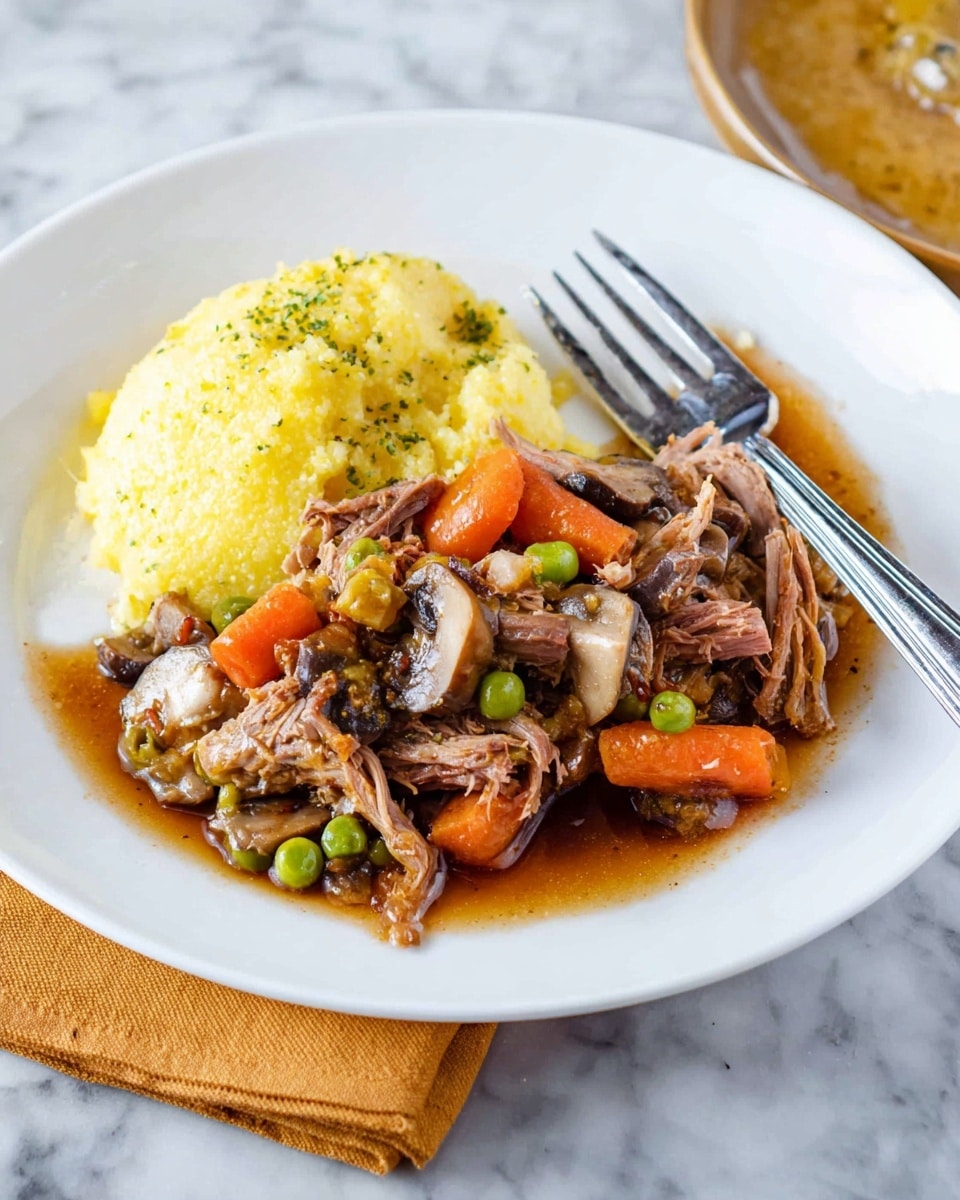 The image shows a white plate on a white marbled surface with a serving of shredded brown meat mixed with green peas, sliced brown mushrooms, and a large orange carrot piece on the left side. On the right side of the plate, there is a thick, creamy yellow layer of soft polenta with a slightly grainy texture. The meat and vegetables are moist with a dark brown sauce that slightly pools on the plate. In the background, there is a rectangular white dish with more meat and vegetables. The photo is taken close-up to highlight the textures and colors of the food. photo taken with an iphone --ar 4:5 --v 7