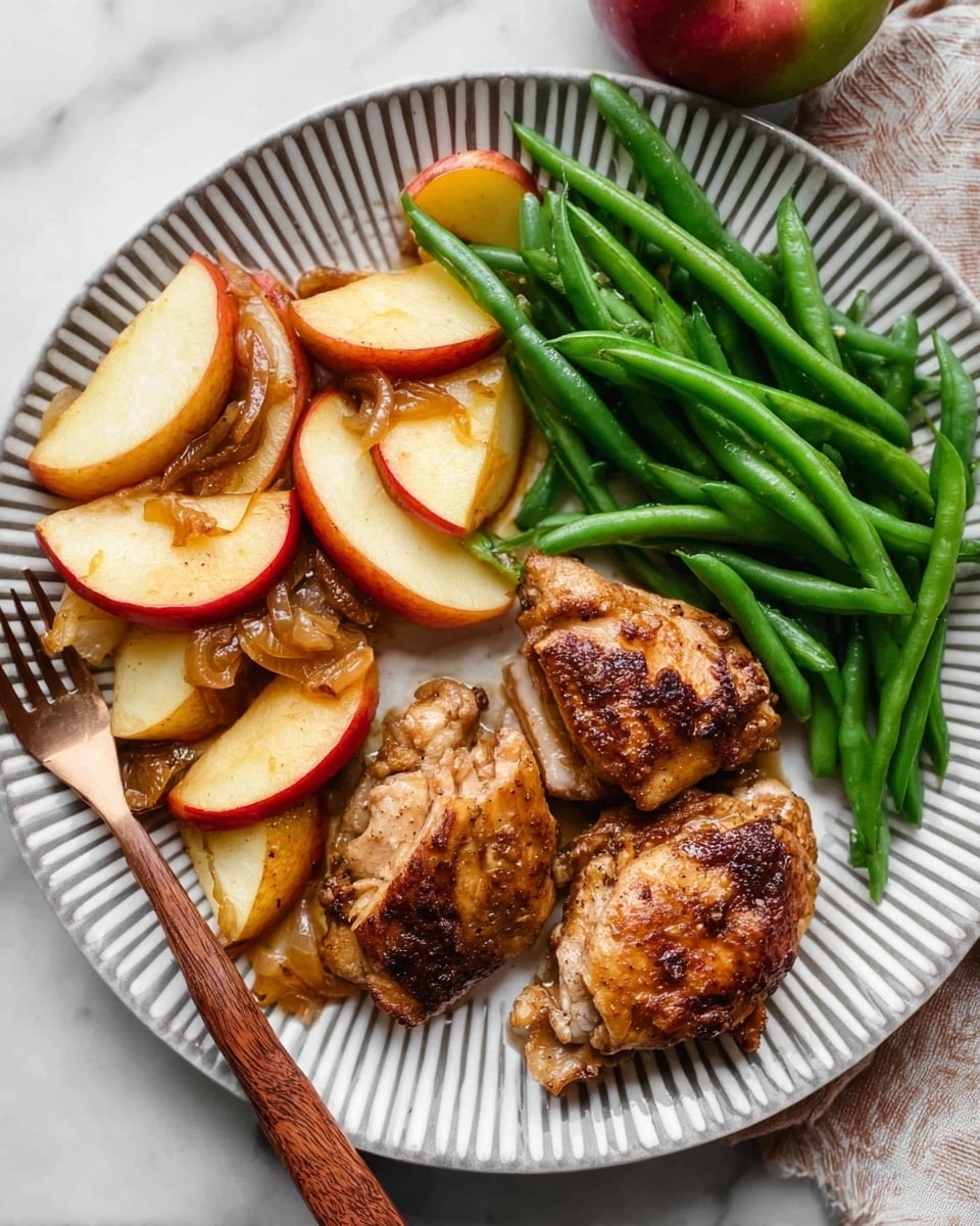 On a white plate with gray stripes, there are three main parts: at the top right, several steamed green beans are placed closely together, bright green in color and smooth in texture; at the bottom right, two pieces of browned chicken thighs sit, topped with four slices of cooked apple that are golden with a slight reddish skin; at the left side, a piece of chicken is sliced into strips with cooked apple slices interspersed, showing a mix of golden brown chicken with caramelized onion bits. The plate is set on a white marbled surface, and a wooden fork rests at the bottom left corner of the plate. photo taken with an iphone --ar 4:5 --v 7