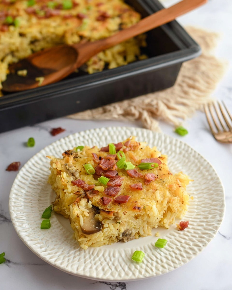 A square piece of yellow baked rice casserole sits on a white textured plate, topped with small pink bacon bits and green chopped scallions scattered over and around it. The casserole looks soft and mixed with bits of light brown cooked onions or mushrooms inside. Behind the plate, there is a black baking pan filled with more of the same rice casserole, with a wooden spoon resting on its edge. The scene is set on a white marbled surface. photo taken with an iphone --ar 4:5 --v 7