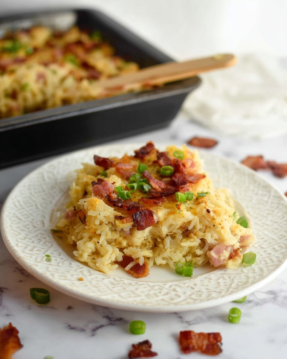 A creamy yellowish rice casserole is served on a white patterned plate, showing three uneven layers of cooked rice mixed with bits of browned onions and small chunks of ham. On top, scattered pieces of crispy pinkish-brown bacon and fresh chopped green onions add contrast and texture. The plate rests on a white marbled surface with some bacon and green onion pieces scattered around for a casual look. In the background, a black baking pan filled with the same casserole and a wooden spatula lay partially blurred. Photo taken with an iphone --ar 4:5 --v 7