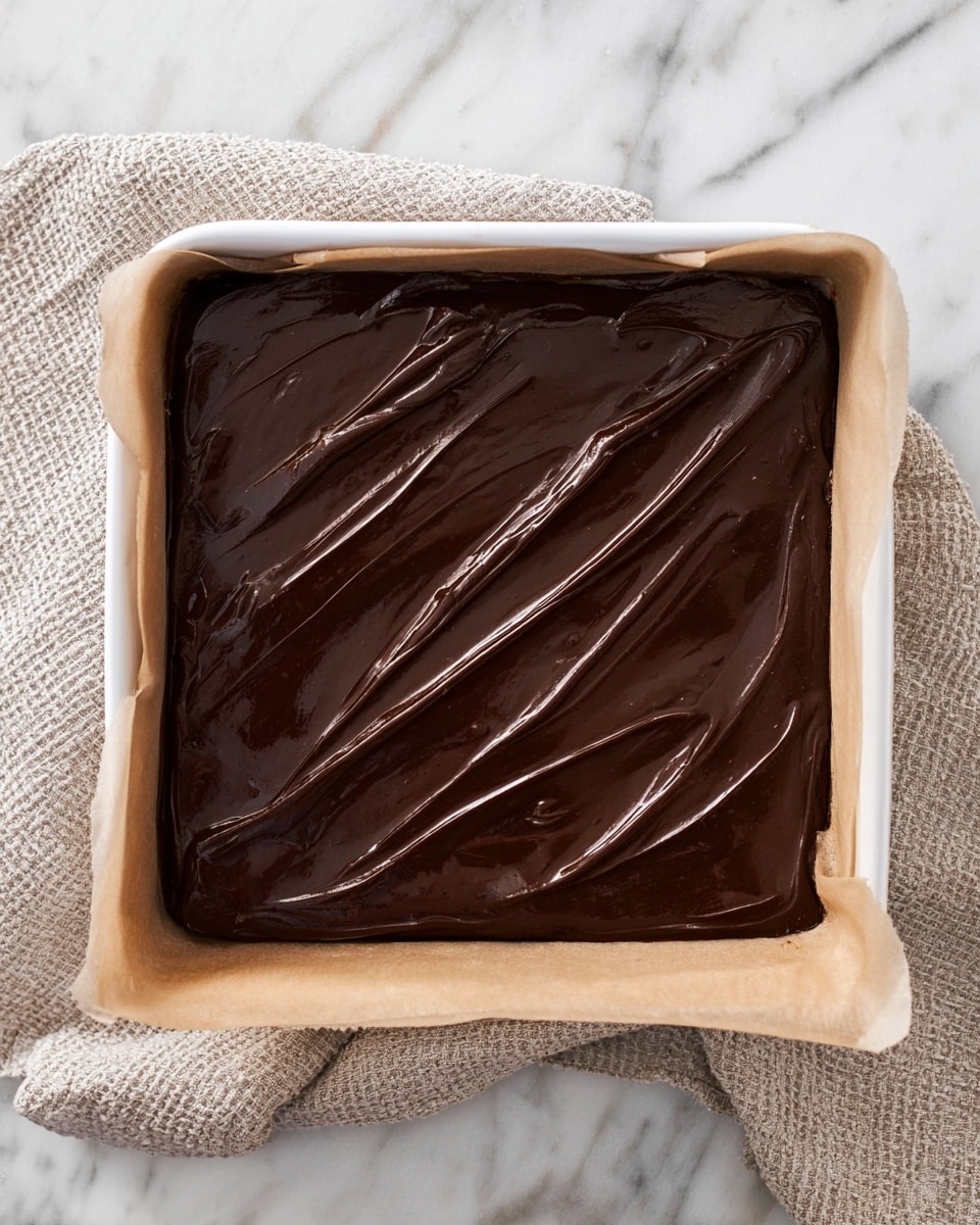 The image shows multiple square chocolate brownies laid out on a white marbled surface. Each brownie has two clear layers: a bottom layer that is dark, moist, and dense with a slightly crumbly texture, and a top layer of smooth, glossy chocolate frosting with soft diagonal ridges. One brownie is turned on its side in the center to show both layers clearly. The brownies are evenly spaced and have sharp, clean edges. photo taken with an iphone --ar 4:5 --v 7
