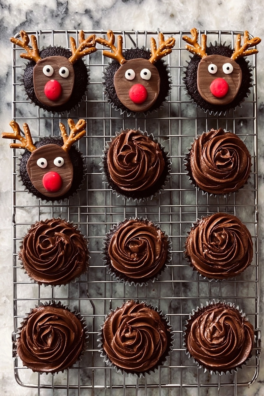 Rudolph Cupcakes with Candy Eyes and Pretzel Antlers Recipe 6 A metal cooling rack holds twelve chocolate cupcakes on a white marbled surface. Seven cupcakes are decorated as reindeer with a smooth, dark chocolate frosting base, topped with a rectangular chocolate piece for the face, two round white candy eyes, a small round red candy nose, and two small pretzel pieces shaped like antlers, placed near the top edges. The other five cupcakes have swirled dark chocolate frosting, with a textured, soft and creamy look, forming a rose-like pattern on top. Photo taken with an iphone --ar 2:3 --v 7 - Rudolph Cupcakes with Candy Eyes and Pretzel Antlers, Rudolph Cupcakes, Christmas Cupcake Ideas, Holiday Baking Recipes, Festive Cupcake Decorations