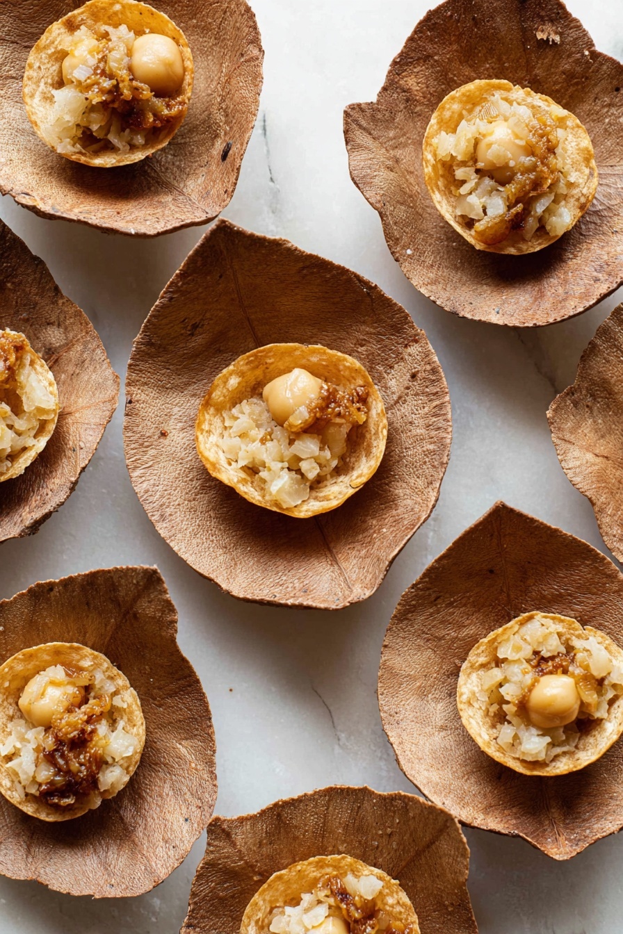 Authentic Pani Puri Recipe 8 The image shows multiple small round puffed snacks placed inside brown leaf-like bowls. Each snack has a thin, crispy golden outer shell with a hollow center holding a filling made of beige and light brown small pieces, possibly chickpeas and some mashed ingredients. The bowls are arranged on a white marbled surface that contrasts with the earthy tones. The puffed snacks show a bubbling texture on their surface, and slight oil sheen is visible. photo taken with an iphone --ar 2:3 --v 7 - Authentic Pani Puri, Pani Puri Recipe, Indian street food, how to make Pani Puri, beginner Pani Puri
