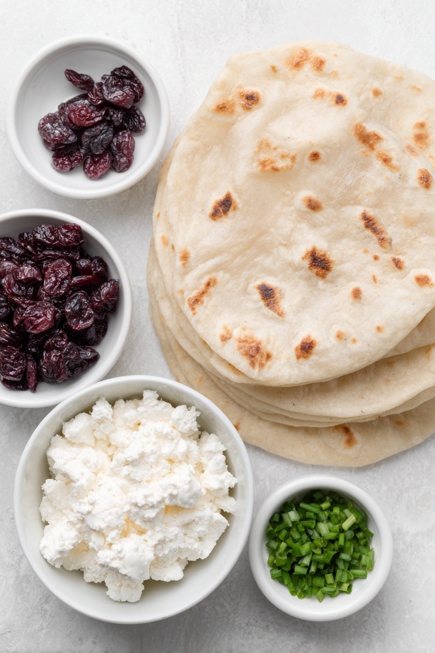 Cranberry Feta Roll-Ups Recipe 7 Flat lay of crumbled sheep’s milk feta cheese in a small white ceramic bowl, softened cream cheese in a small white ceramic bowl, sweetened dried cranberries scattered naturally, four whole large flour tortillas stacked neatly, chopped fresh chives in a small white ceramic bowl, all arranged with perfect symmetry and balanced proportions placed on a clean white marble surface, soft natural light, photo taken with an iPhone, professional food photography style, fresh ingredients, white ceramic bowls, no bottles, no duplicates, no utensils, no packaging --ar 2:3 --v 7 --p m7354615311229779997 - Cranberry Feta Roll-Ups, festive appetizer recipes, holiday party snacks, make-ahead appetizer ideas, easy holiday appetizers
