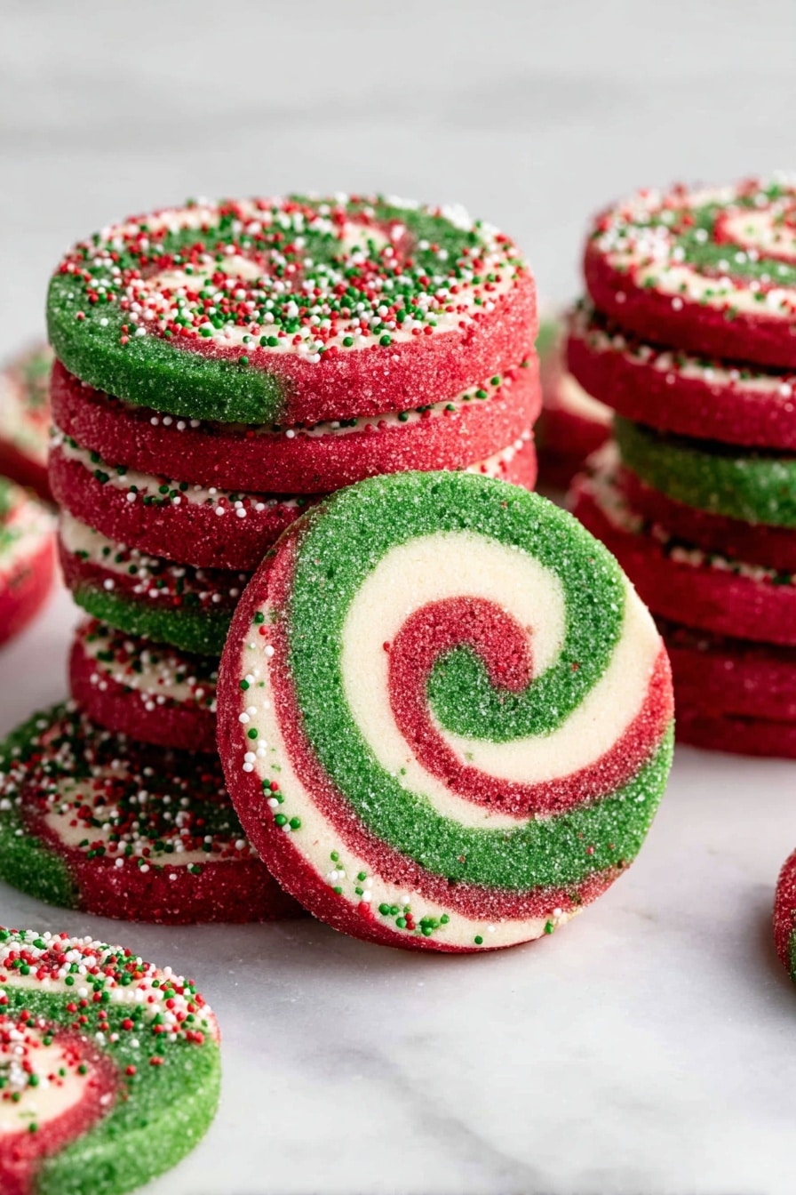 Christmas Pinwheel Cookies Recipe 6 The image shows a stack of round cookies with three visible spiral layers: the outer red layer covered with small red, green, and white round sprinkles, a middle white layer, and an inner green layer, all swirled together. The cookies are thick and have a rough texture on the edges due to the sprinkles. Around the stack, some cookies lie flat, showing the spiral pattern clearly. The scene is set on a white marbled surface, and the lighting highlights the bright colors and textures of the cookies. photo taken with an iphone --ar 2:3 --v 7 - Christmas Pinwheel Cookies, festive cookie recipes, holiday sugar cookies, colorful swirl cookies, easy Christmas baking