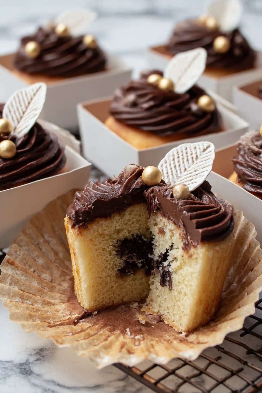 The image shows multiple small square brown paper boxes filled with chocolate cupcakes. Each cupcake is topped with swirled dark chocolate frosting that has a smooth and glossy texture. On top of the frosting are two white chocolate leaves placed side by side, standing upright in the center. Around the leaves, there are small, round, shiny gold-colored edible balls scattered evenly on the frosting. The boxes sit on a white marbled surface with a minimal background. The photo is taken with an iphone --ar 2:3 --v 7 - Autumn Chocolate Cupcakes with Gold Decorations, festive fall cupcakes, elegant chocolate cupcakes, gold decorated cupcakes, autumn dessert recipes