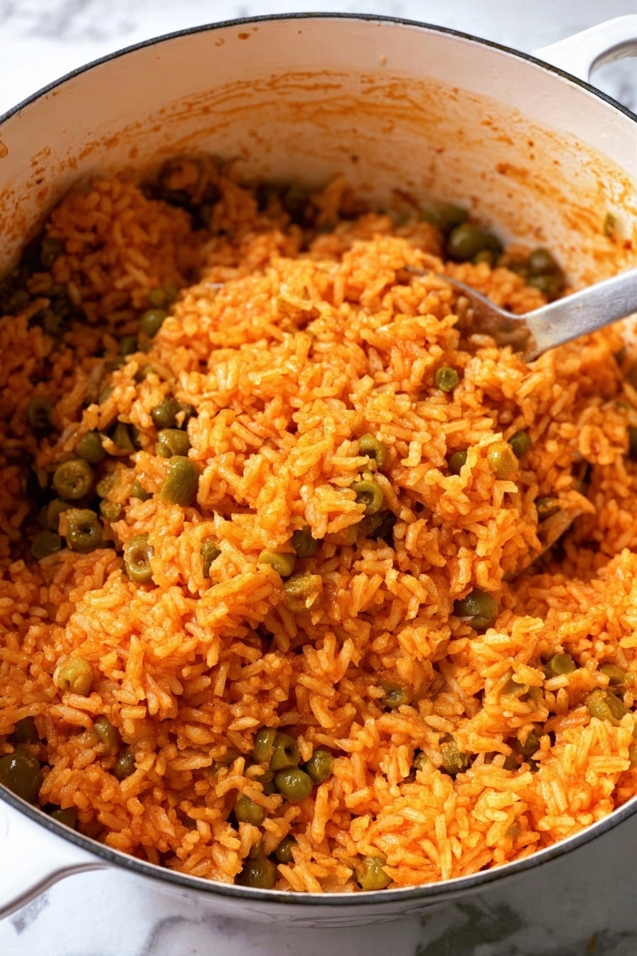 Puerto Rican Arroz Con Gandules Recipe 6 The image shows a close-up of a large white pot filled with cooked rice that is orange in color, mixed with green peas and green olives. The rice has a moist and slightly textured look with some grains sticking together. The inside sides of the pot have some rice stains, showing it has been cooked directly in the pot. The pot is resting on a white marbled surface. A metal spoon is partially visible, scooping some of the rice from the pot. photo taken with an iphone --ar 2:3 --v 7 - Puerto Rican Arroz Con Gandules, Puerto Rican rice recipes, Authentic Puerto Rican dishes, Gandules recipe, Traditional Puerto Rican rice