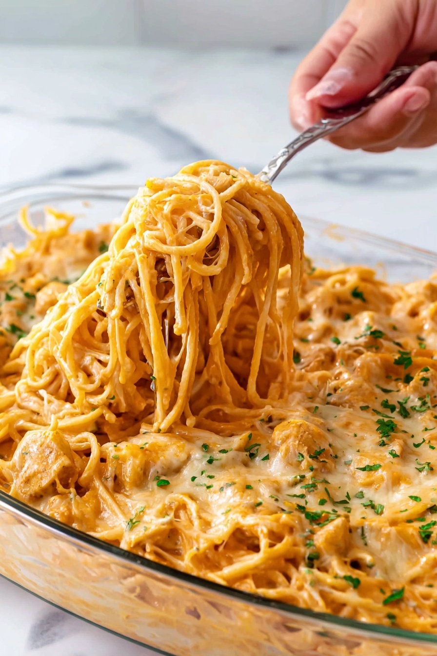 Creamy Chicken Spaghetti Bake Recipe 6 A clear glass dish filled with creamy orange spaghetti noodles layered with melted cheese and small pieces of chicken, topped with chopped green herbs. A woman's hand is using a silver fork to lift a thick bunch of the spaghetti from the dish, showing the noodles coated in sauce and cheese. The dish sits on a white marbled surface. photo taken with an iphone --ar 2:3 --v 7 - Creamy Chicken Spaghetti Bake, cheesy pasta casserole, easy chicken pasta dish, comforting chicken bake recipe, weeknight dinner idea
