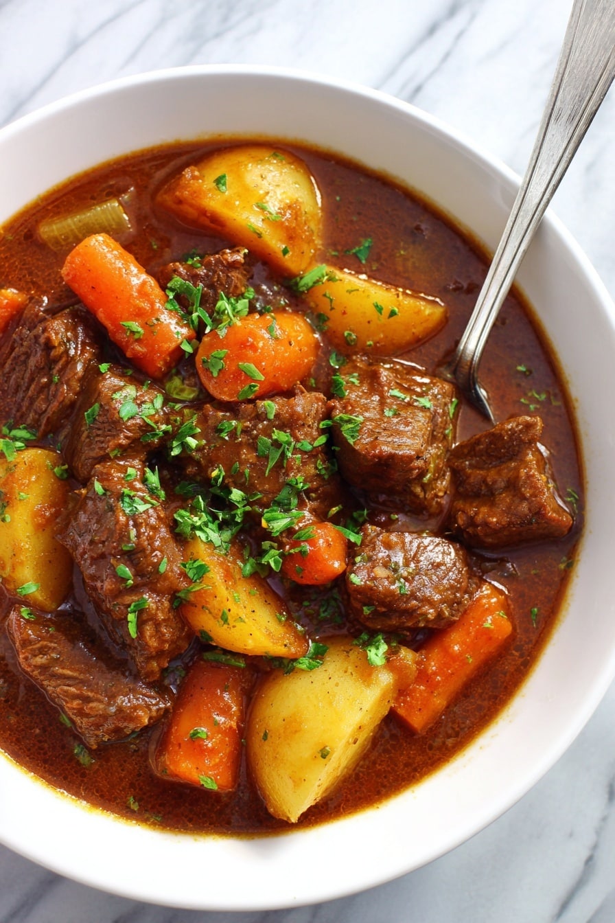 This image shows a white bowl filled with a thick beef stew. The stew has many large pieces of brown beef, orange carrot chunks, yellow potato slices, and small pieces of celery mixed in a rich brown sauce. The stew is topped with chopped green herbs. A shiny silver spoon rests inside the bowl. The bowl is placed on a white marbled surface. photo taken with an iphone --ar 2:3 --v 7 - Slow Cooker Beef Stew, hearty beef stew, easy slow cooker recipes, comforting beef dinner, tender beef stew recipe