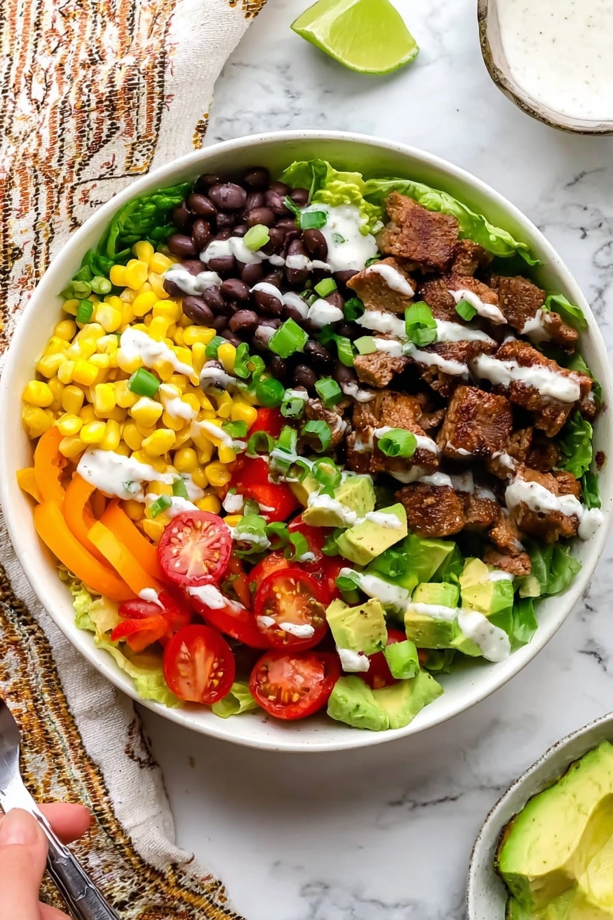 Southwest Steak Salad with Chili Lime Chicken Recipe 6 A white bowl filled with layers of colorful ingredients arranged in sections. The bottom layer is fresh green lettuce. On top of the lettuce, there are bright yellow corn kernels on one side, black beans next to the corn, and sliced yellow bell peppers beside the beans. Cherry tomato halves add a pop of red near the edge. Cooked brown meat pieces take up a large section, garnished with green onion slices. Diced green avocado pieces sit near the meat. A lime wedge rests on the lettuce near the edge of the bowl. White creamy dressing is drizzled over the ingredients unevenly. The bowl is placed on a white marbled surface with a beige and brown patterned cloth nearby, a woman's hand holding a spoon is visible at the bottom left corner. photo taken with an iphone --ar 2:3 --v 7 - Southwest Steak Salad with Chili Lime Chicken, chili lime chicken recipe, Southwest steak salad, spicy chicken salad, healthy steak salad