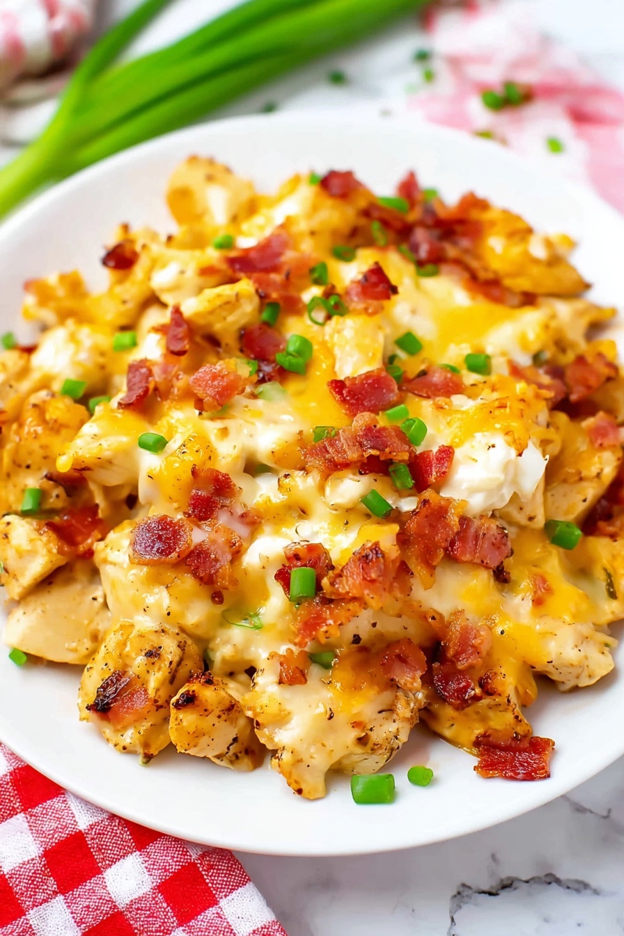 Creamy Chicken Bacon Ranch Casserole Recipe 6 The dish shows a white plate filled with several layers of food. At the bottom, there are pieces of light golden-brown cooked chicken mixed with diced crispy bacon bits scattered all over. On top, melted yellow and white cheese covers the chicken and bacon with a bubbly, slightly browned texture. Small green onion pieces are sprinkled across the dish for color contrast. The background surface is a white marbled texture with some green onions lying near the plate and a red and white checkered cloth in the corner. photo taken with an iphone --ar 2:3 --v 7 - Creamy Chicken Bacon Ranch Casserole, chicken bacon ranch casserole, cheesy chicken dinner, easy weeknight casseroles, comfort food recipes
