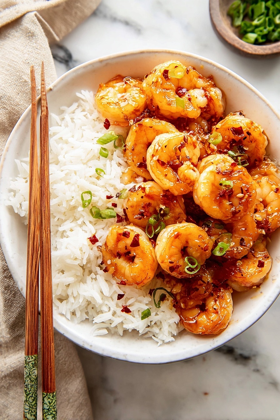 Sweet Honey Garlic Shrimp Recipe 8 A white bowl filled with a base layer of white rice with a fluffy texture, topped with a thick pile of glazed shrimp. The shrimp are golden-orange, shiny with sauce, and sprinkled with small green herb pieces. The shrimp layer has a slightly glossy and sticky texture with small bits of red chili flakes mixed in. To the side of the bowl are wooden chopsticks resting on the edge, and the background shows a white marbled surface with a blurred beige cloth and a green bowl with leafy greens. Photo taken with an iphone --ar 2:3 --v 7 - Sweet Honey Garlic Shrimp, honey garlic shrimp, quick seafood dishes, easy shrimp recipes, flavorful seafood dinner