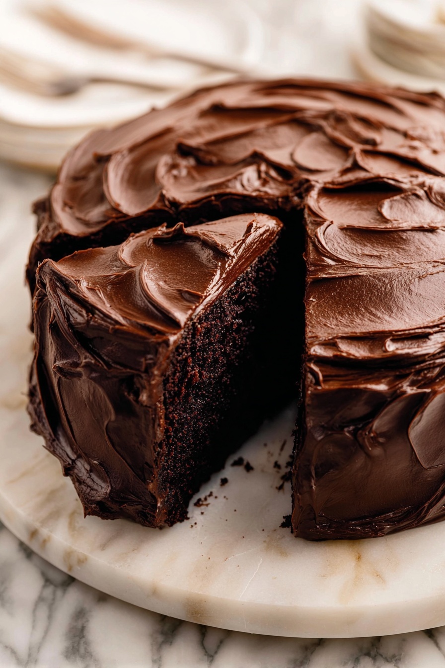 Decadent Chocolate Cake with Fudge Frosting Recipe 6 A round chocolate cake with one thick slice removed sits on a white marble platter. The cake is covered fully in rich, glossy chocolate frosting that is thickly spread with swirling, textured waves all over the top and sides. The inside of the cake layer shows a dark, dense chocolate crumb. The white marble platter contrasts with the deep brown of the cake, and the background has a white marbled texture. Photo taken with an iphone --ar 2:3 --v 7 - Decadent Chocolate Cake with Fudge Frosting, chocolate cake recipe, moist chocolate cake, fudge frosting recipe, rich chocolate dessert