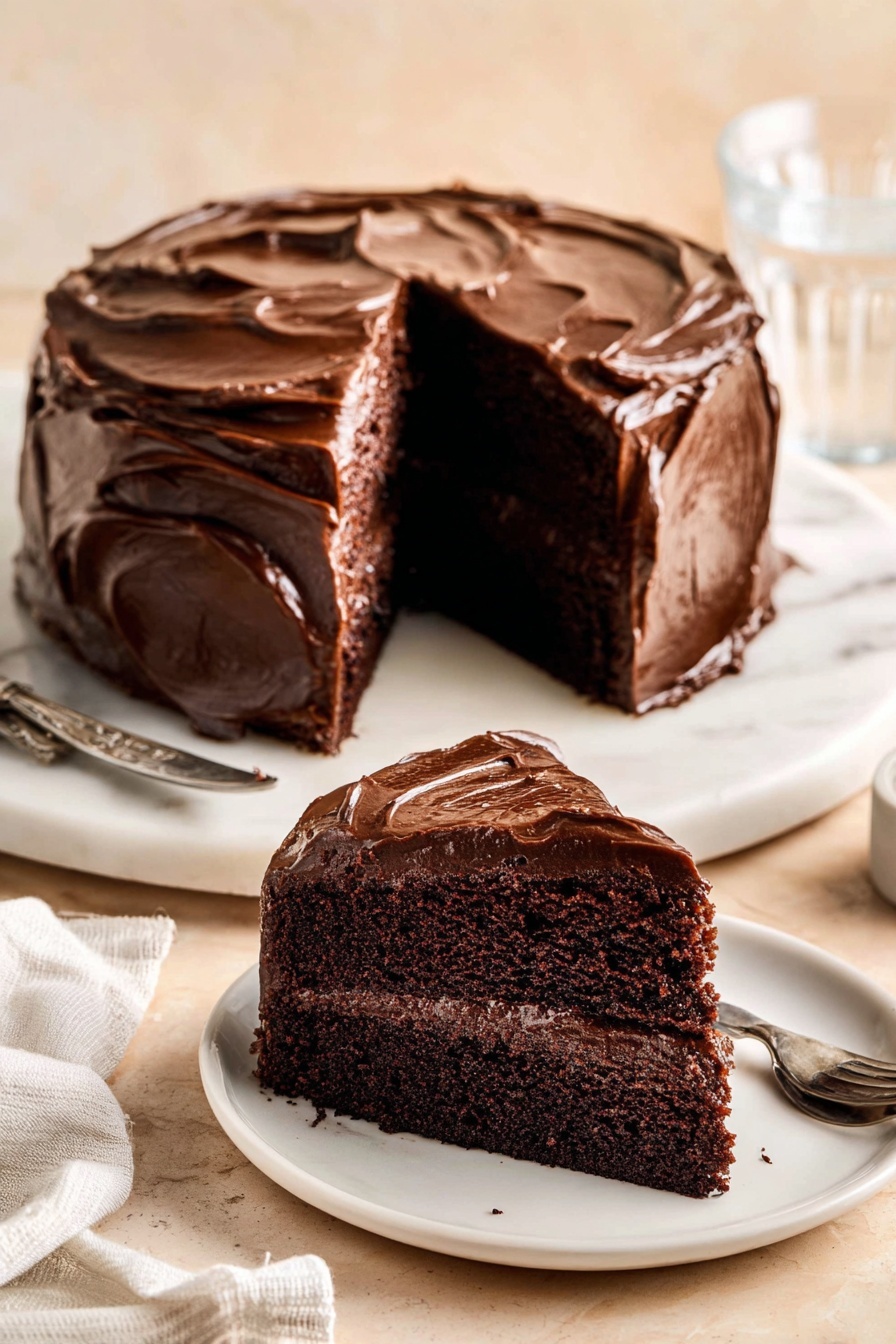 Decadent Chocolate Cake with Fudge Frosting Recipe 8 A two-layer dark chocolate cake covered in thick, shiny chocolate frosting with visible swirling texture on the top and sides, the rich dark brown cake layers inside are moist with a smooth chocolate filling between them; one slice is removed and placed on a white plate in front, showing the inside clearly, all set on a round white marble board with a soft beige background and a glass of water and white cloth in back; photo taken with an iphone --ar 2:3 --v 7 - Decadent Chocolate Cake with Fudge Frosting, chocolate cake recipe, moist chocolate cake, fudge frosting recipe, rich chocolate dessert