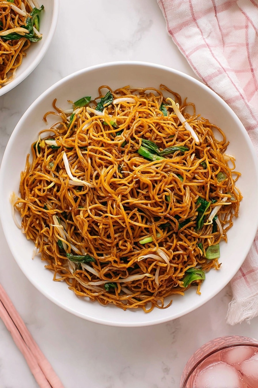 Quick Cantonese Chicken Chow Mein Recipe 6 A white shallow bowl is filled with a single layer of dark golden brown fried noodles, with thin light brown bean sprouts and bright green leafy vegetables mixed evenly throughout. The noodles look lightly shiny, tangled, and crispy. The bowl sits on a white marbled surface next to a light pink and white checkered cloth and pink chopsticks, adding soft pastel tones to the image. Part of another white bowl of food and a pink glass with ice are visible at the edges. Photo taken with an iphone --ar 2:3 --v 7 - Quick Cantonese Chicken Chow Mein, Easy Asian Chicken Noodle Stir-Fry, 15-Minute Chicken Chow Mein, Restaurant-Quality Chicken Chow Mein, Quick Weeknight Dinner Recipes