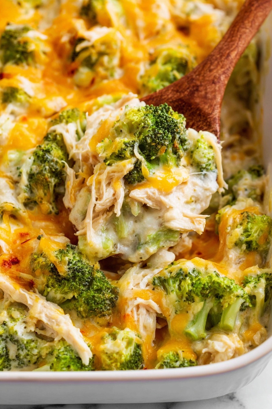 The image shows a close-up of a creamy broccoli casserole served in a white dish against a white marbled surface. The casserole has layers that include bright green broccoli florets mixed with shredded chicken pieces in a white creamy sauce. On top, there is a generous layer of melted yellow and white cheese, creating a slightly stringy and soft texture. A wooden spoon is scooping a portion from the bottom left, showing the mix of broccoli, chicken, and cheese in detail. The colors are warm and vibrant, highlighting the creamy and cheesy texture of the dish. photo taken with an iphone --ar 2:3 --v 7 - Chicken Bacon Ranch Casserole, Chicken Bacon Ranch skillet, cheesy chicken bacon bake, quick ranch chicken casserole, flavorful chicken bacon dish