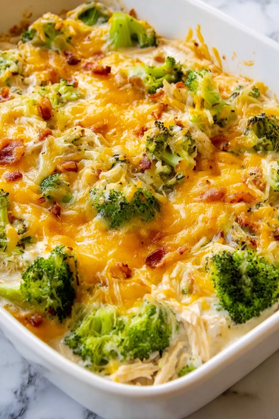 Chicken Bacon Ranch Casserole Recipe 8 The dish is a baked casserole with multiple layers starting at the base with shredded chicken mixed in a creamy white sauce. On top are bright green broccoli florets spread evenly across the dish. Covered over everything is a layer of melted cheddar and white shredded cheese bubbling slightly with some browned spots. The surface shows a mix of creamy, cheesy, and green textures with some bits of browned onions or bacon pieces sprinkled throughout. The dish is inside a white baking dish set on a white marbled surface. photo taken with an iphone --ar 2:3 --v 7 - Chicken Bacon Ranch Casserole, Chicken Bacon Ranch skillet, cheesy chicken bacon bake, quick ranch chicken casserole, flavorful chicken bacon dish
