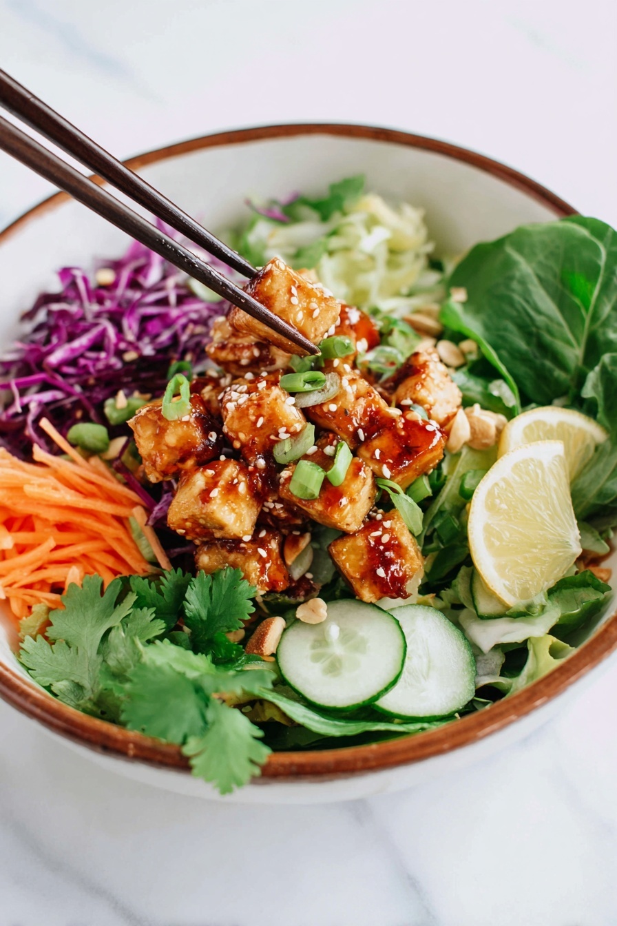 Spicy Tofu Salad Bowls Recipe 8 A white bowl with a brown rim holds a colorful salad arranged in layers; the bottom layer has mixed green leaves and sliced green onions, followed by thin orange carrot sticks and purple cabbage on one side. On top of the vegetables are small golden-brown tofu cubes coated with sesame seeds and chopped peanuts, drizzled with a reddish sauce. There are green cucumber slices and lemon wedges placed around the tofu. A pair of dark brown chopsticks is picking up some tofu from the bowl, and some fresh cilantro leaves garnish the salad. The bowl is set on a white marbled surface. Photo taken with an iphone --ar 2:3 --v 7 - Spicy Tofu Salad Bowls, healthy tofu salad, quick vegetarian dinner, crunchy veggie bowls, flavorful tofu recipes